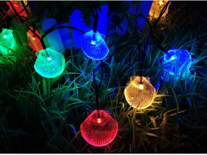 Colorful LED shell string lights glowing on nighttime garden grass for outdoor decoration
