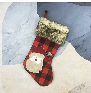 Detail of red buffalo plaid Christmas stocking with faux fur trim and Santa Claus patch