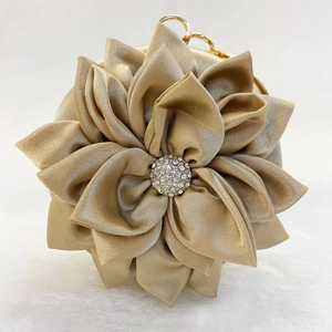 Detail of champagne satin evening bag with 3D floral petals and rhinestone center