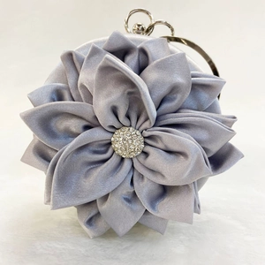 Detail of silver silk evening bag featuring 3D floral folds and crystal rhinestones