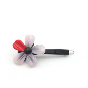 Barrette à cheveux florale en acétate avec pétales rouges et roses sur fond blanc
