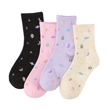 Close-up of pastel cotton socks featuring embroidered planet, moon and star patterns