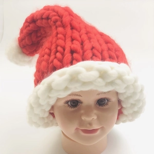 Close-up of thick red knit Christmas hat with white pompom on a display model