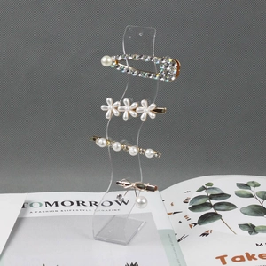 Elegant hairpin set with pearls and rhinestones displayed on a clear wavy rack