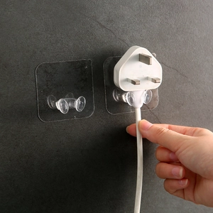 Transparent adhesive wall hook for power plugs showing easy cable management on gray wall