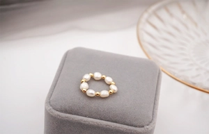 Close-up of elegant freshwater baroque pearl elastic ring with gold beads on jewelry box