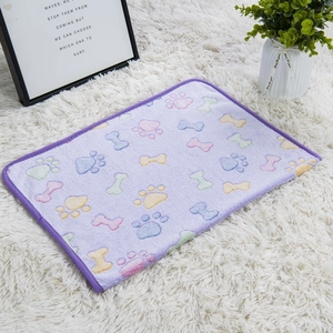 Close-up of purple flannel pet blanket with colorful paw and bone prints on white rug