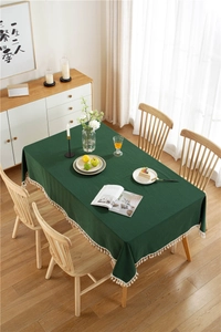 Detailed view of dark green washed cotton tablecloth with white decorative tassels