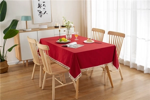 Detailed view of red washed cotton tablecloth with white pom-pom fringe accents