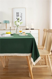 Detail of dark green cotton tablecloth with white wavy tassel fringe texture