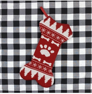Detail of red and white bone-shaped Christmas stocking with festive paw and snowflake motifs