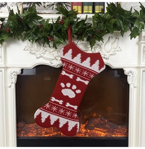 Detail showing red and white knitted bone-shaped Christmas stocking on a festive fireplace