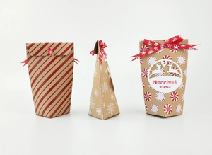 Trois boîtes cadeaux de Noël en papier kraft avec motifs festifs et rubans rouges