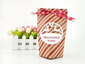 Gros plan d'un sac cadeau de Noël en papier kraft rayé avec sceau de renne et ruban