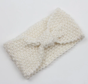 Detailed close-up of white chunky knit headband with central knot butterfly design