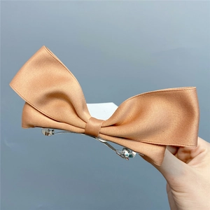 Detailed close-up of a large satin ribbon bow hair clip with a metal spring fastener