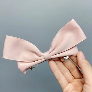Detail of pink satin ribbon bow hair clip with high-quality metal spring fastener