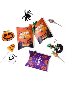 Flat lay of colorful Halloween pillow boxes with ribbons, candy, and festive props