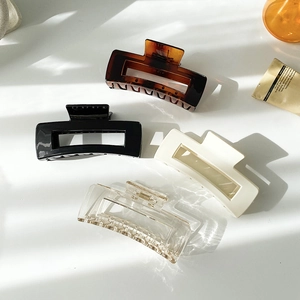 Detailed view of large square hair claws in tortoiseshell, black, cream, and clear finishes