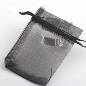 Macro shot of black organza drawstring jewelry pouch with silver ring inside