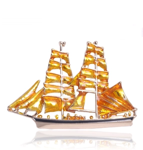 Detail showing a golden sailing boat brooch with rhinestone accents and yellow enamel finish
