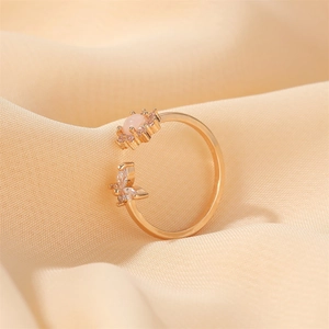 Macro detail of golden butterfly ring with pink opal and zircon micro-inlay accents