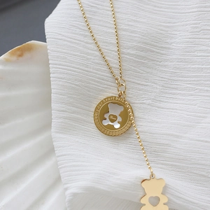 Detail of rose gold bear necklace with white mother-of-pearl inlay and tassel heart charm