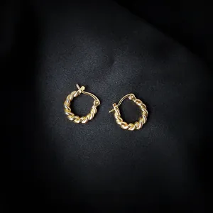 Detailed view of handmade twisted gold hoop earrings on black silk background