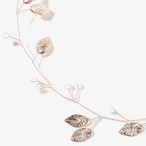 Close-up of rose gold leaf charms on delicate bridal hair vine for wedding styling