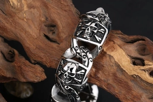 Macro shot of punk style skull link bracelet with vintage silver finish on dark wood