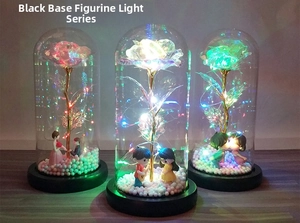 Detail view of colorful foil rose in glass dome with couple figurines and LED lights