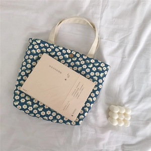 Detail of navy floral canvas tote bag featuring white daisy patterns and snap button