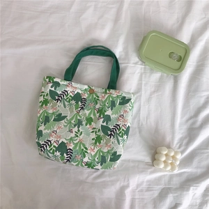 Detail of tropical plant print canvas bag with green handle and gold snap button closure