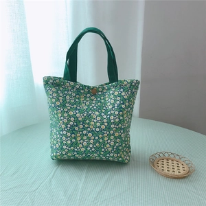 Detail of green floral canvas lunch bag with daisy pattern and retro metal snap button