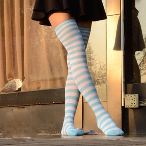Gros plan détaillé de chaussettes hautes rayées bleu et blanc avec mini-jupe noire