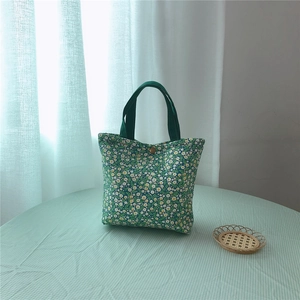 Detail of floral canvas tote bag with daisy pattern and green ribbon handle closure