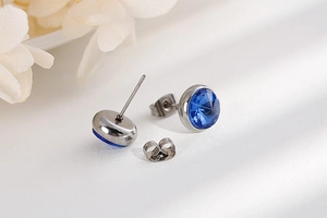 Close-up of blue crystal stud earrings with polished silver-tone metal backing and butterfly clutch