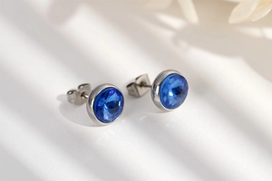 Close-up of elegant round blue zircon earrings with minimalist silver settings