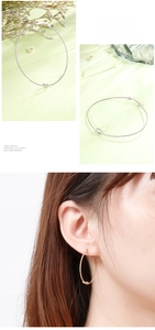 Detail of twisted knot hoop earrings in gold and silver finish on model