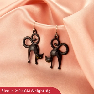 Detail of gothic black cat earrings with yellow eyes over pink silk background