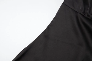 Dettaglio macro del tessuto satinato nero e cuciture sottili su un vestito a V
