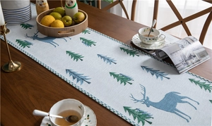 Detail of blue chenille table runner with deer and tree jacquard on a wooden table
