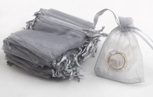 Close-up of gray drawstring organza gift bags showing texture and capacity with a ring