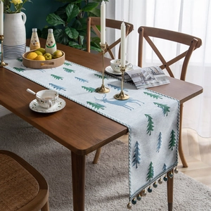 Modern chenille table runner with elk and pine tree patterns featuring beaded tassels