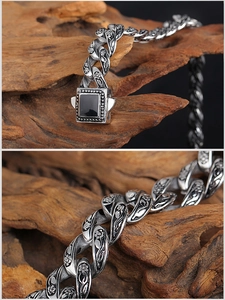 Macro view of vintage silver steel Cuban chain with floral carvings and black resin buckle
