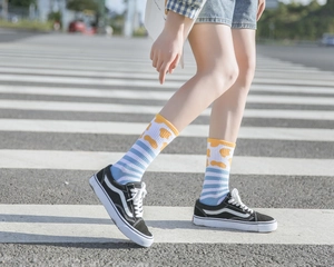Close-up of blue white striped crew socks with yellow pattern styled with black sneakers