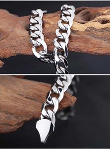Détail macro d'un bracelet gourmette argenté poli avec fermoir métallique lisse sur bois