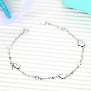 Detail of s925 silver bracelet with heart charms and sparkling stones on a white background