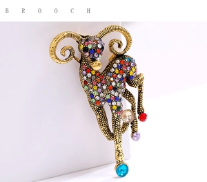 Macro detail of hand-painted goat brooch with colorful crystals and vintage gold finish