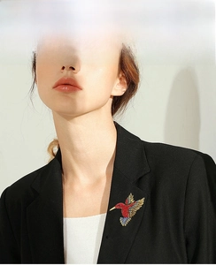 Detailed view of luxury hummingbird brooch with colorful rhinestones on a black suit lapel